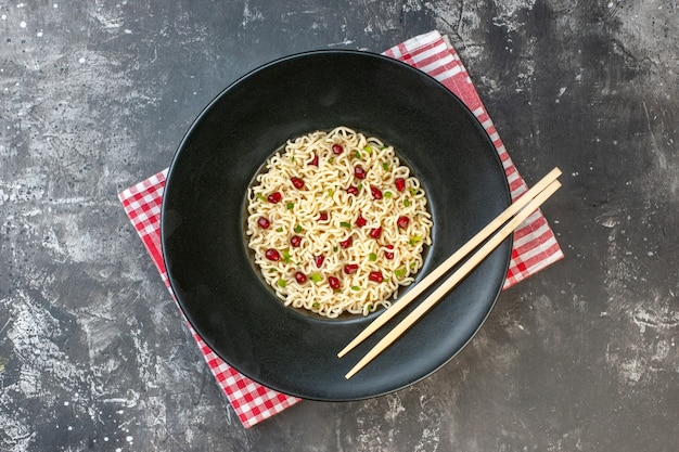 Top view ramen noodles chopsticks on dark round plate