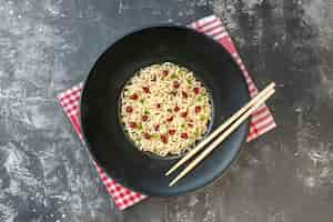 Free photo top view ramen noodles chopsticks on dark round plate