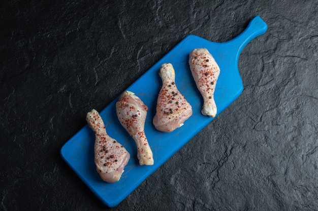 Free photo top view raw chicken drumstick on blue wooden board.