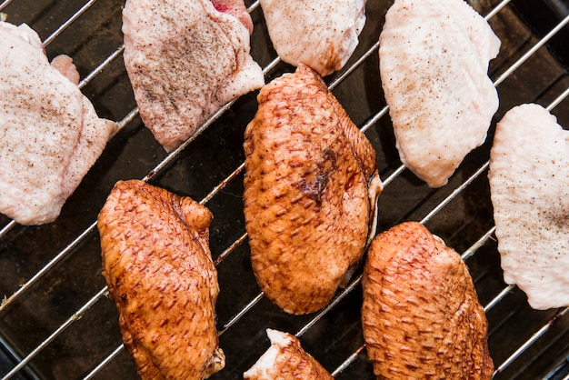 Top view of raw chicken wings on metal grill