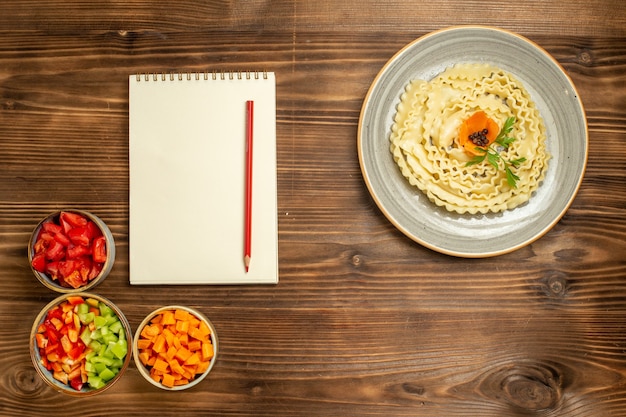 Top view raw dough pasta with different seasonings on brown wooden background dough food pasta meal