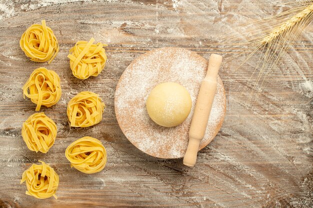 Top view raw dough pasta with flour on wooden brown background dough meal food pasta