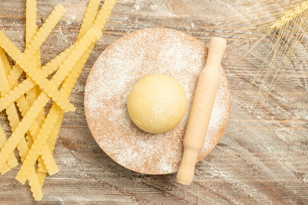 Top view raw dough pasta with flour on a wooden brown background dough raw meal food pasta