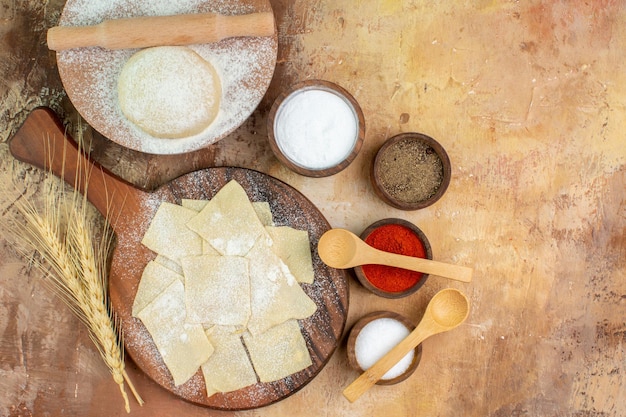 Top view raw dough slices with flour on cream desk