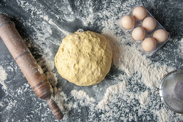 Top view raw dough with eggs and white flour on dark background dough egg bakery hotcake pastry kitchen cuisine