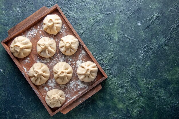 Top view raw dumplings with meat inside on dark background color meal pepper dough meat flour dish cooking