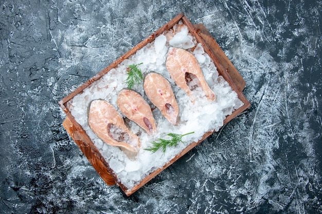 Free Photo top view raw fish slices with ice on wood board on grey background copy place