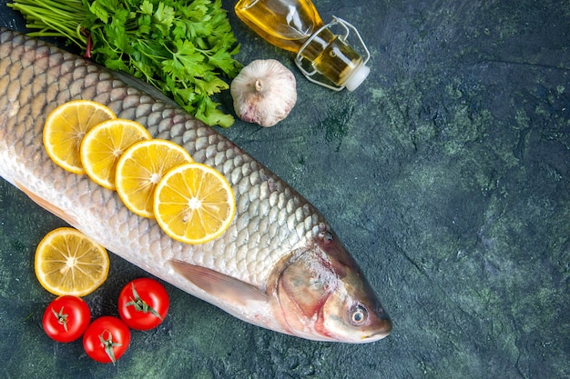 Top view raw fish tomatoes lemon slices oil bottle on table free space