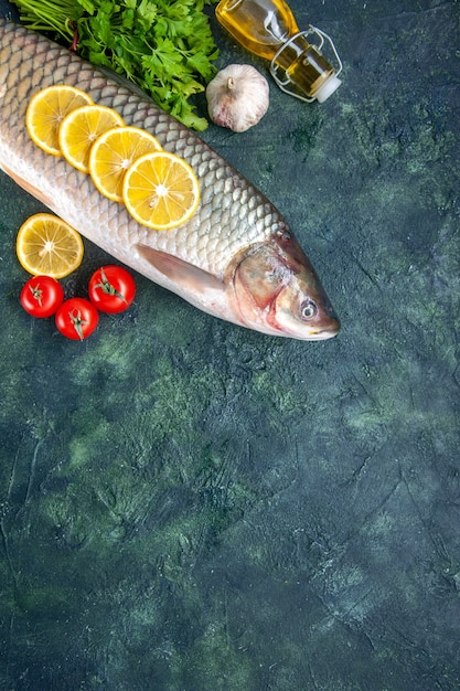 Free photo top view raw fish tomatoes lemon slices oil bottle on table with free space