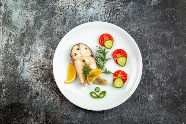 Free photo top view of raw fishes and pepper fresh foods on white plate on gray ice surface