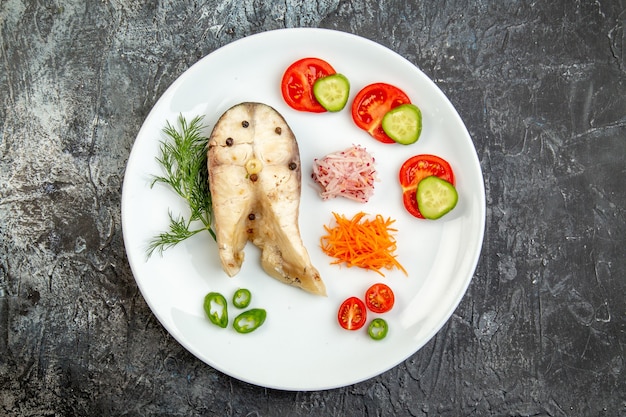 Top view of raw fishes and pepper fresh foods on white plate on ice surface