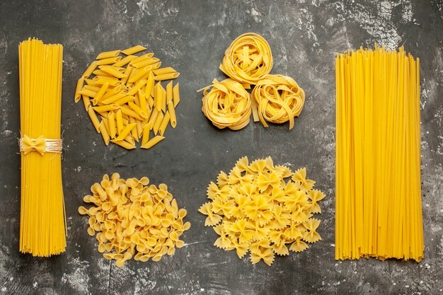 Top view raw italian pasta different formed on the light-grey background