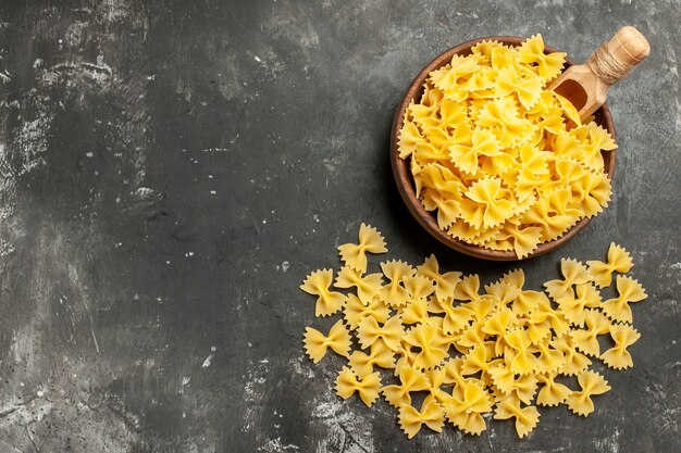 Top view raw italian pasta inside plate on dark-grey background