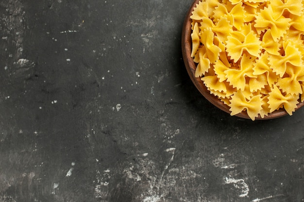 Top view raw italian pasta inside plate on dark-grey background