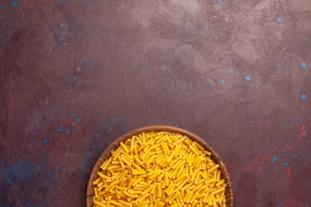 Top view raw italian pasta little formed on dark-purple background vegetable pasta meal food color