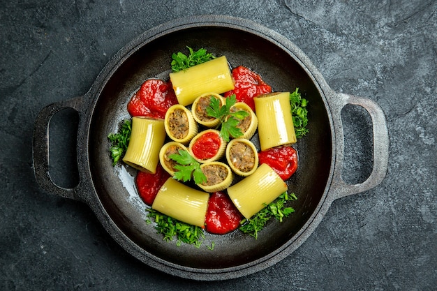 Top view raw italian pasta with meat greens and tomato sauce inside pan on a dark background pasta dough meal food