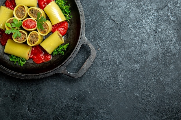 Top view raw italian pasta with meat greens and tomato sauce inside pan on the dark background pasta dough meal food