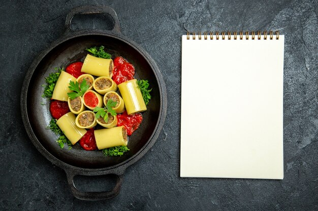 Top view raw italian pasta with meat greens and tomato sauce inside pan on dark grey background pasta dough meal food