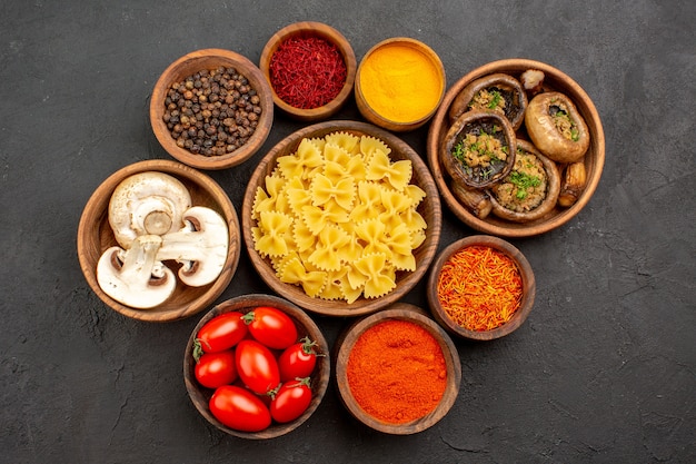 Free photo top view raw italian pasta with seasonings and mushrooms on dark background