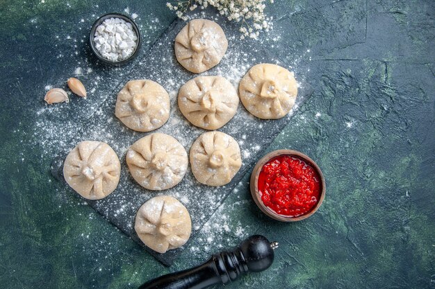 Top view raw little dumplings with meat inside on dark surface flour meat pepper color cooking meal cuisine dish dough