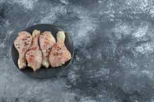 Free photo top view of raw marinated chicken legs on black plate.