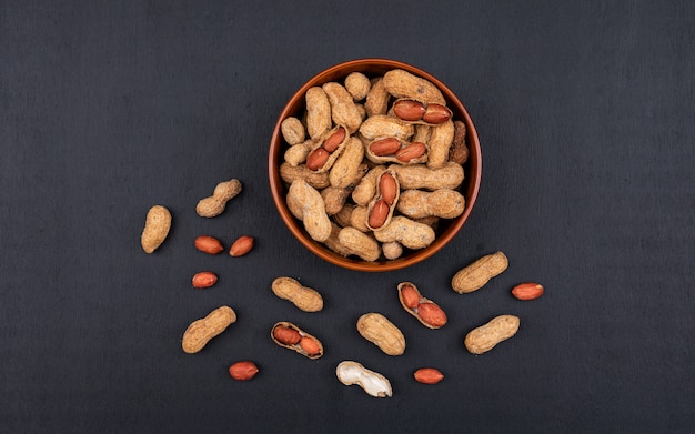 Top view raw peanuts in bowl on black  horizontal