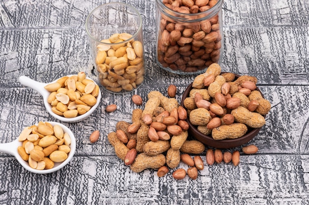 Top view raw peanuts in bowl, jar and plates horizontal