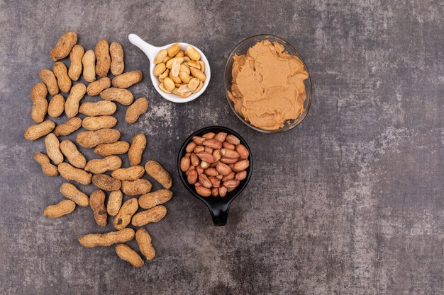 Top view raw peanuts in bowl and peanut butter on stone  horizontal