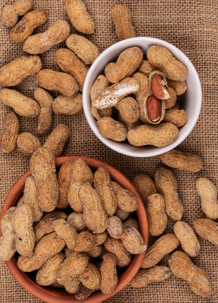 Top view raw peanuts in bowl on sackcloth vertical