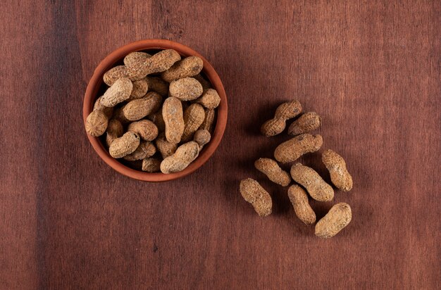 Top view raw peanuts in bowl on wooden brown  horizontal