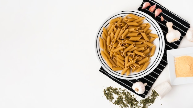 Free Photo top view of raw penne pasta and it's ingredients on white backdrop