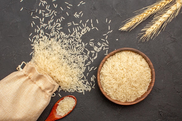 Top view of raw rice inside bag and plate on grey surface