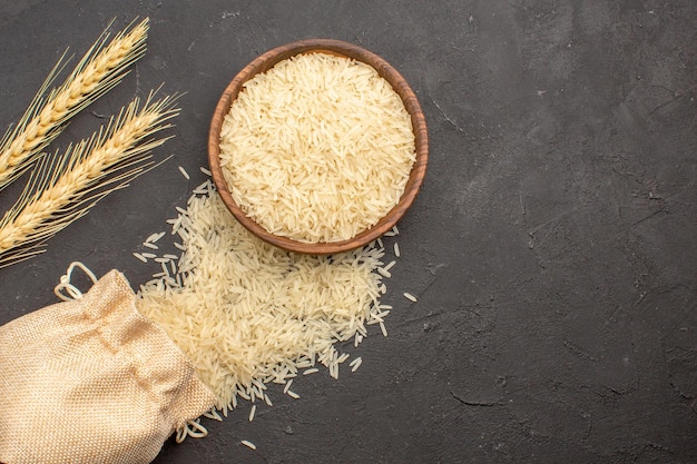 Top view of raw rice inside brown plate on grey surface