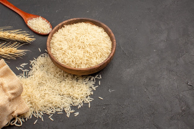 Top view of raw rice inside brown plate on grey surface