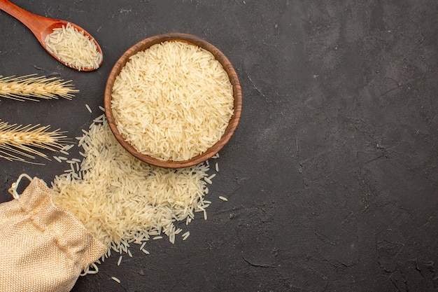 Top view of raw rice inside brown plate on the grey surface