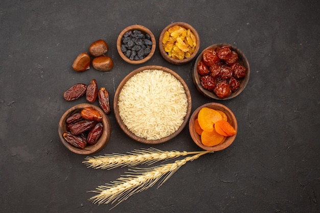 Top view of raw rice with different raisins on a grey surface