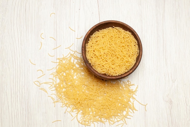 Top view of raw vermicelli inside brown plate on white