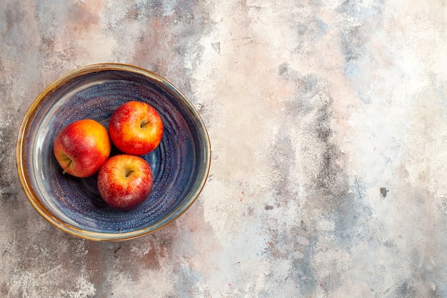 Free photo top view red apples in bowl on nude surface copy place