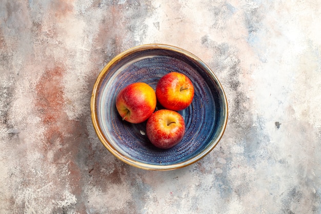 Top view red apples in bowl on nude surface free space