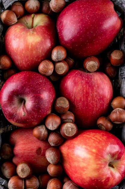 Top view red apples with nuts in basket texture vertical