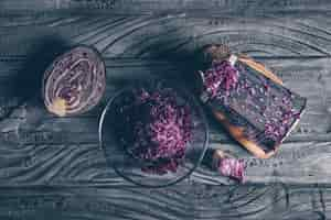 Free photo top view red cabbage with vegetable grater and grated cabbage on dark wooden background. horizontal