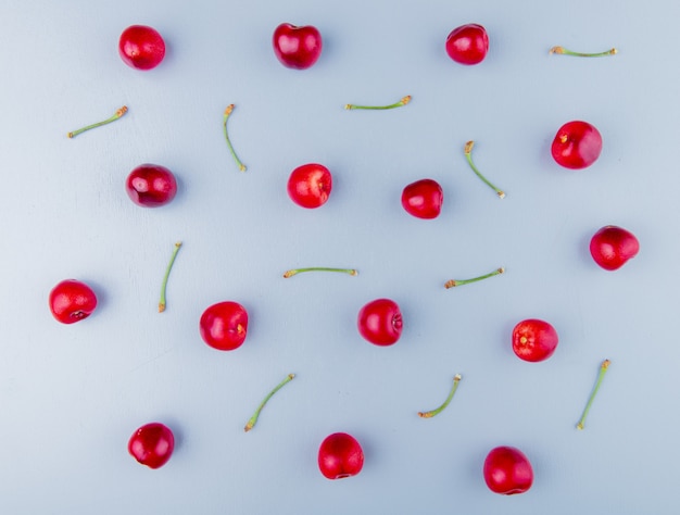 Top view of red cherries with stems on blue surface