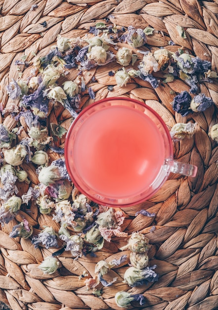 Free photo top view red colored water on trivet background with tea herbs vertical