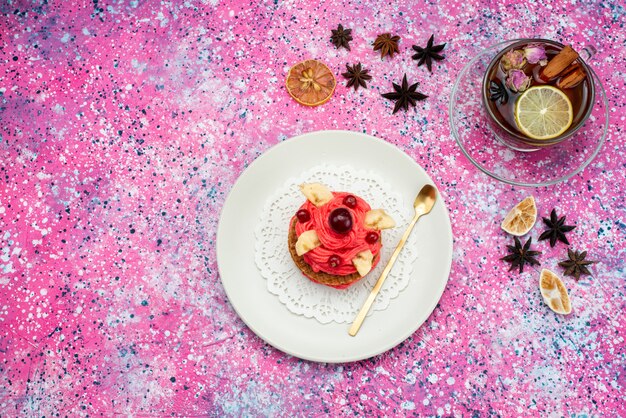 Top view red creamed cake with hot tea on the colored background cake biscuit sweet sugar color