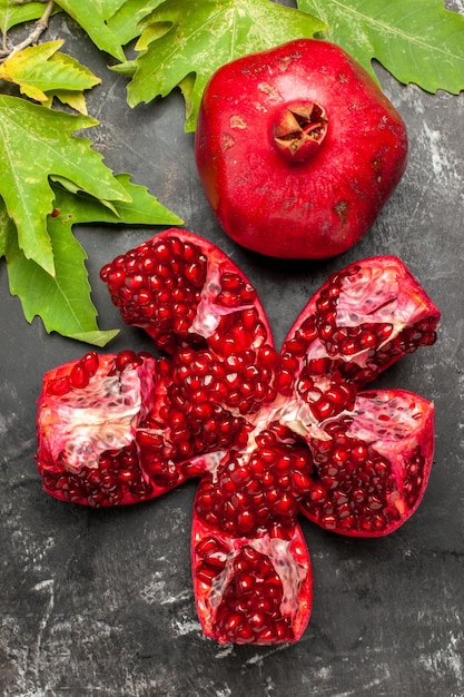 Top view red fresh pomegranate with green leaves on dark surface