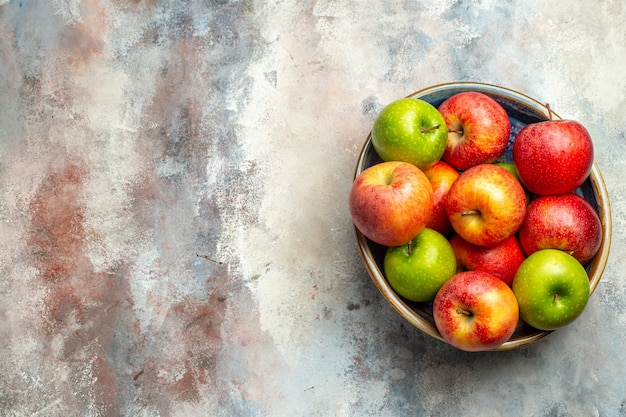 Top view red and green apples in bowl on nude surface copy space