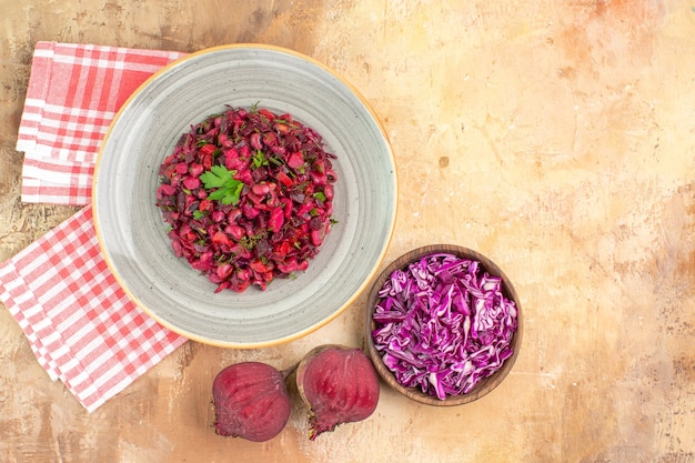 Top view red healthy salad dressed with parsley leaves made of beetroots and bowl of chopped cabbage on a wooden background with copy place