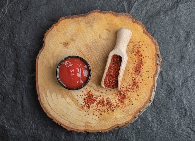 Free photo top view of red hot chili pepper with ketchup on wooden board.