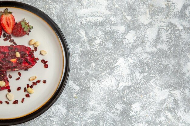 Top view red nougat sliced with nuts and fresh red strawberries on white desk