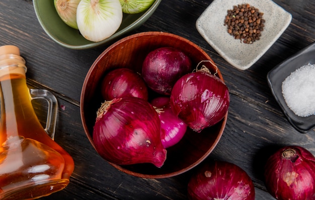 Free photo top view of red onions in bowl with bowl of white onions melted butter black pepper salt around on wooden background